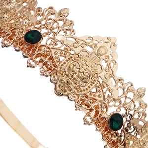 Detailed close-up of a gold baroque crown featuring intricate filigree and green emerald stones