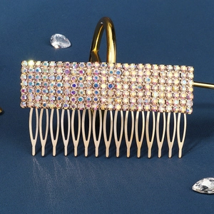Detailed close-up of a gold bridal hair comb with iridescent rhinestones on blue surface