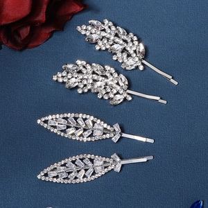 Détail de barrettes argentées avec motifs de feuilles et plumes ornées de strass brillants