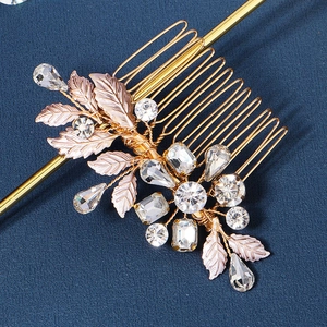 Close-up of golden bridal hair comb with crystal rhinestones and textured metal leaves