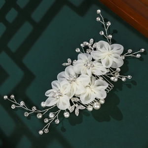 Détail du peigne de mariée avec fleurs en tulle, perles blanches et strass brillants