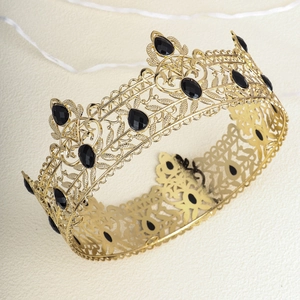 Macro detail of baroque golden alloy crown with intricate leaf patterns and black gemstones
