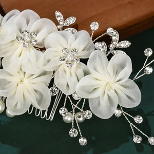 Détail d'un peigne de mariée avec fleurs en tulle blanc, strass et perles