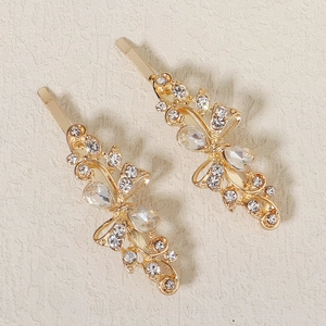 Detailed close-up of golden metal hair clips with hollow floral designs and clear crystals