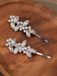 Détail de barrettes feuilles argentées avec strass brillants sur support en bois