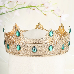 Detail of vintage gold baroque crown with emerald green gems on a display head