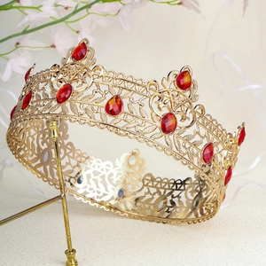 Close-up of golden baroque crown featuring red teardrop gemstones and floral hollow patterns