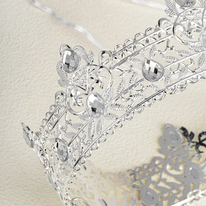 Close-up of silver baroque crown featuring intricate filigree and pear-cut rhinestones