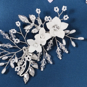 Macro detail of bridal hair comb featuring ceramic flowers, pearls, and crystals