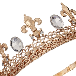 Detail of baroque gold crown featuring fleur-de-lis patterns and clear oval crystals