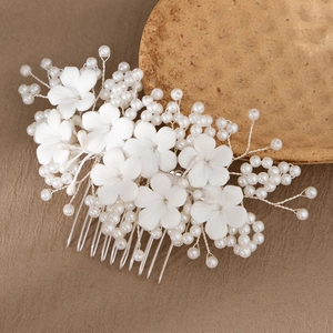 Detailed view of handmade white ceramic flower and pearl hair comb for bridal wedding style