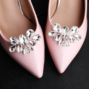 Detailed macro view of square rhinestone shoe clips with sunburst pattern on pink leather