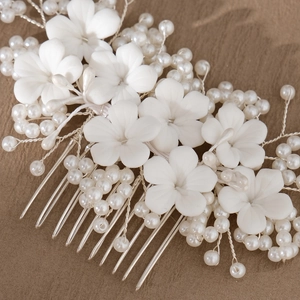 Macro detail of bridal hair comb featuring white resin flowers and woven faux pearls