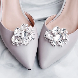 Close-up of sparkling crystal flower clips on elegant lavender pointed-toe bridal shoes