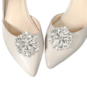 Close-up of radiant sunflower rhinestone buckles on ivory pointed-toe bridal shoes