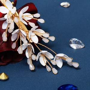 Macro view of handmade floral hair clip with gold wire and white enamel petals