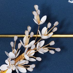 Macro shot of handmade gold wire floral hair clip with white petals and beaded details