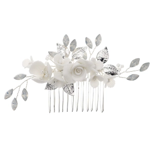 Macro detail of bridal hair comb featuring white ceramic flowers and crystal leaves