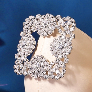 Macro shot of square crystal flower shoe clip with sparkling rhinestones on beige leather