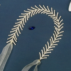 Détail d'un serre-tête à strass avec rubans en mousseline blanche sur fond bleu