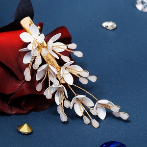 Elegant gold and white floral hair clip featuring metal petals on dark blue background