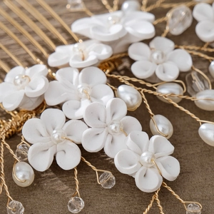 Macro shot of bridal hair comb with ceramic flowers and pearls on a wooden texture