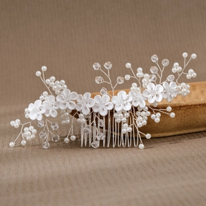 Detail of handmade bridal hair comb with ceramic flowers, pearls, and crystals on a stand