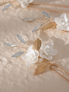 Macro shot of bridal hair comb with ceramic flowers, gold leaves and white pearls
