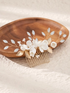 Detail of bridal hair comb with white ceramic flowers, gold leaves and blue beads