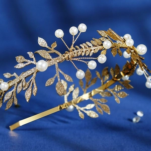 Détail du serre-tête avec feuilles dorées et perles blanches sur tissu bleu chic