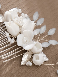 Macro detail of handmade bridal hair comb featuring ceramic tulip flowers and silver leaves