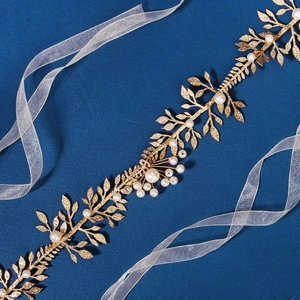 Détail du bandeau de mariée à feuilles dorées avec perles blanches sur tissu bleu
