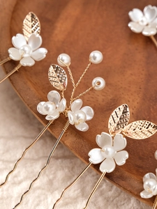 Detailed close-up of handmade bridal hair pins with ceramic flowers and pearls set on gold