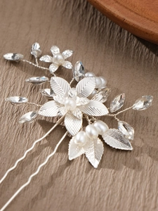 Detail of silver bridal hair comb with pearls, crystals, and delicate metal flowers