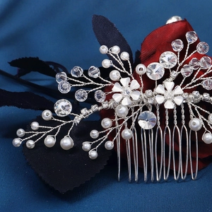 Close-up of bridal silver hair comb with white pearls, crystals and delicate floral motifs