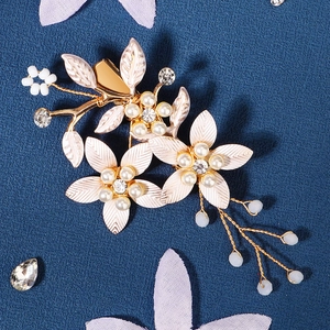 Détail d'une pince à cheveux fleurie faite main avec perles et pétales en métal doré