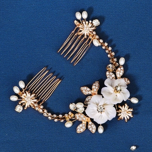 Detailed shot of golden wedding hair comb with white shell flowers and pearls on blue background