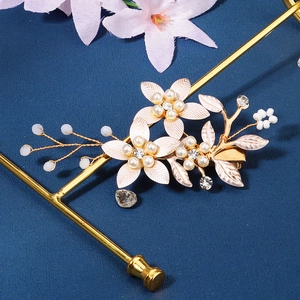 Détail d'une pince à cheveux fleur rose avec perles et strass sur support doré