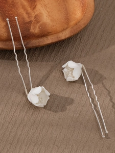 Detailed macro view of white ceramic flower hair pins with silver wavy U-shaped sticks