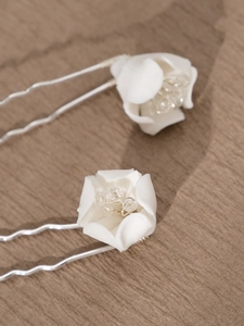 Detail of two handmade bridal hair pins with white ceramic flowers and crystal beads