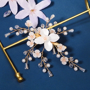 Détail d'une pince à cheveux florale artisanale avec pétales blancs et perles de cristal