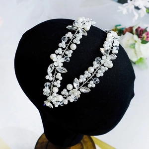 Elegant bridal headband with white pearls, crystals and floral details on a black model head