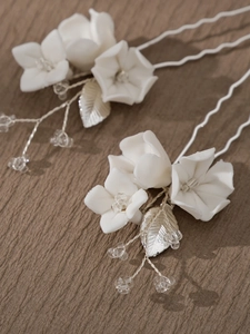 Detail of white ceramic flower hair pins with silver leaves and crystals for bridal hair