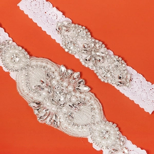 Dettaglio della giarrettiera da sposa in pizzo con strass marquise e perle d'avorio