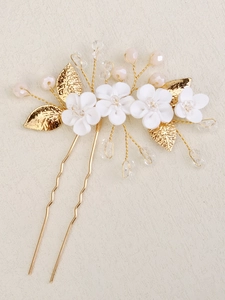 Close-up of bridal hair comb with white ceramic flowers and golden leaf details