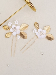 Detail of bridal hair pins with white resin flowers, gold leaves, and sparkling crystals