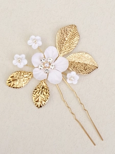 Detailed close-up of handmade bridal hair comb with ceramic flowers and golden leaves