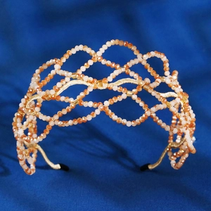 Handwoven champagne crystal headband with orange beads and gold mesh design on blue velvet