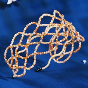 Handmade champagne crystal woven headband with gold mesh design on a velvet background