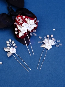 Detailed macro view of handmade white ceramic flower hair pins with silver leaves and pearls